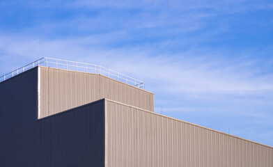 Fototapeta na wymiar Modern Aluminium Industrial Factory Building with steel fence on rooftop against blue sky background, low angle and perspective side view