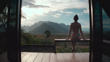 Woman relax in holiday hut villa with mountain wild nature view. Female in bikini enjoy tropical...