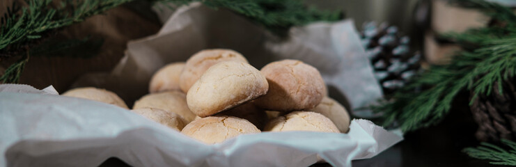 lemon crinkle cookies in bakery paper decorated with corns, pine tree branches, cozy winter family holidays with homemade baked bisquits