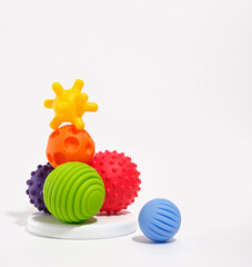 Colored different tactile or sensory balls on a white round stand for development the cognitive and physical processes of children. Copy space for text. - obrazy, fototapety, plakaty