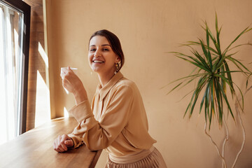 Candid portrait of laughing young woman wearing casual clothes holding cup of coffee