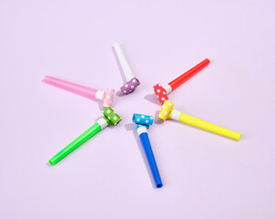 Party blowers different colors on a purple background. Birthday and friendly atmosphere.