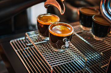 Close up of Espresso shot with coffee crema and Professional coffee machine while preparing two espressos shot glass in a coffee shop.