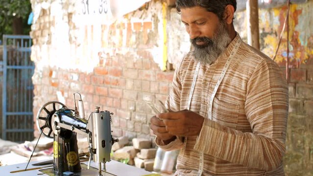 A man counting Indian currency notes - daily earnings   self-employed  Aatmanirbhar Bharat  India  employment . The tailor checking his wages - financial freedong  financial saving  saving for goal...