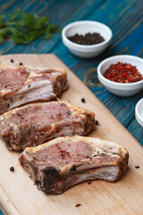 Raw pork ribs with spices and herbs on cutting board on wooden background