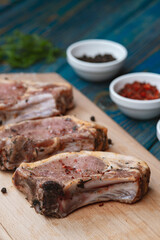 Raw pork ribs with spices and herbs on cutting board on wooden background