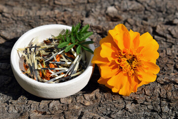 Orange tagetes flower with seeds and leaves in a small bowl 