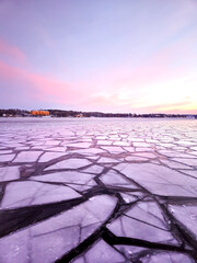 Ice sheets on sea in winter at sunrise on early Scandinavian morning with purple and pink sky in...