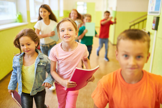 Schoolgirl running in corridor with friends - Powered by Adobe