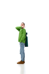 Young man with trash bin on his back throwing cigarette, taking care after planet isolated over white background. Concept of environment, ecology, nature care, recycling, awareness