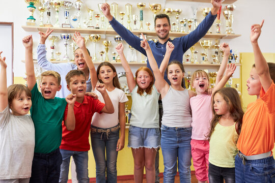 Teacher and students cheering near trophy shelf