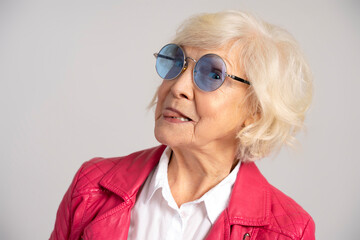 Fototapeta premium Elderly joking woman licking out lips with tongue and looking at camera
