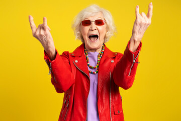 Front view of grey hair screaming caucasian woman showing rock gesture