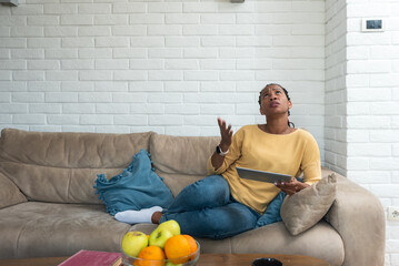 African American woman sitting at home in apartment having issue and headache because of loud noise...