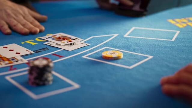 Close Up on Casino Baccarat Gambling Table: Anonymous Croupier Dealing Playing Cards on a Blackjack Table with Bet Chips in Place. Poker Chips are Being Exchanged as the Lucky Guest Wins the Jackpot