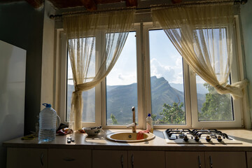 Kitchen countertop with sink and gas stove with window and view of mountain top of Gunib plateau in Dagestan