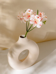 Vase with flower bouquet on the table with aesthetic sunlight shadows. Ceramic vase with pink flowers, bohemian home poster, interior decoration