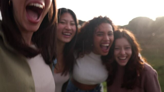 Smiling selfie of a cheerful group of young people. Video call of excited happy friends having fun. interracial girls taking pictures looking at mobile smart phone camera. Enjoying the vacations