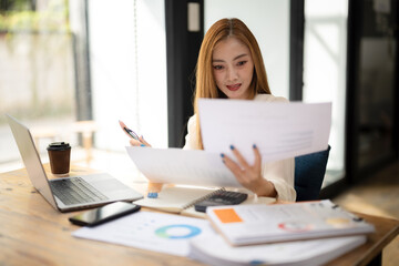 Fototapeta premium Businesswoman sitting work at desk, reviews project planning with marketing calculations for plans and results.