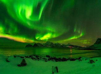 Obraz na płótnie Canvas Breathtaking mountain view with vibrant green lights illuminating the night sky