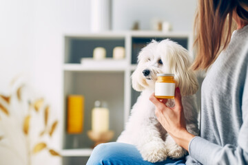 Supplements for pets. Woman with small cute dog holds in her hand medicine jar of animal vitamins against blurred interior. Concept of animal wellness, vitamins for animal, holistic pet health. Mockup - obrazy, fototapety, plakaty