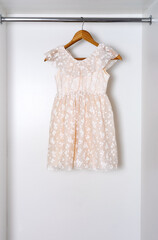 White children dress on hanger in white wardrobe.