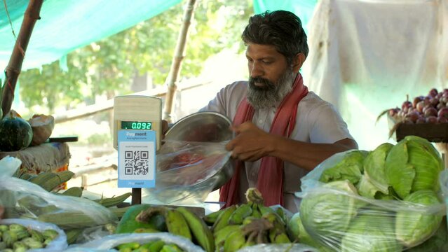 Indian street vendor selling tomatoes in the street market - fresh tomatoes  measurement  single-use plastic ban  plastic use. A vegetable seller selling vegetables - accurate measurement  vendor s...