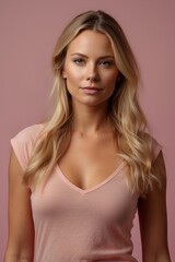 Fototapeta premium Close-up of a portrait of a beautiful young blonde girl model with plump lips, green eyes looking at the camera on a pink background.