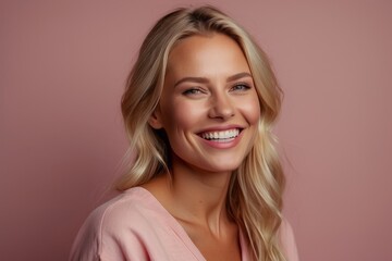 Close-up portrait of a happy smiling young blonde woman looking at the camera on a pink background. Positive emotions, facial expression concepts.