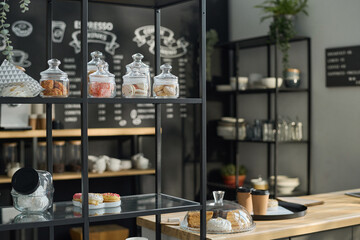 Displays with tasty cookies and other snacks in jars and trays standing in front of camera next to counter with order of client