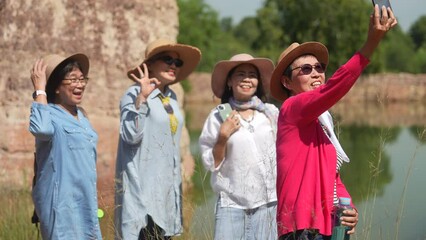 Group of Asian senior aging women using technology smartphone taking photo selfie together on holiday vacation, healthy elderly pensioner females happy hiking traveling enjoy activities outdoors