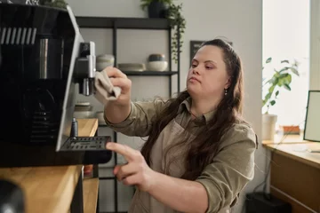 Foto op Plexiglas Young woman with mental disability wiping details of coffee machine with wet duster before preparing cappuccino for clients of cafe © pressmaster