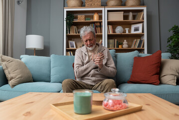 Elderly aged senior man sitting alone in the dark of his apartment depressed and sad after the loss...