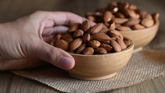 Raw almond nut seeds in a bowl with hand