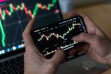 Smartphone with mobile application cryptocurrency wallet. A man analyzes the price chart for bitcoin in a mobile application. The concept of cryptocurrency trading