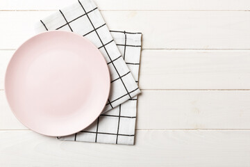 Top view on colored background empty round pink plate on tablecloth for food. Empty dish on napkin...