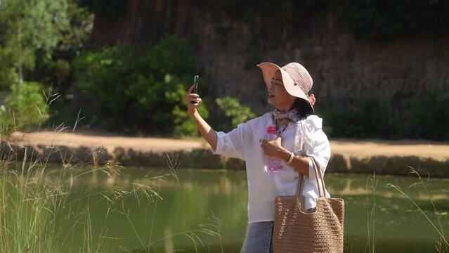 Group of Asian senior aging women using technology smartphone taking photo selfie together on holiday vacation, healthy elderly pensioner females happy hiking traveling enjoy activities outdoors