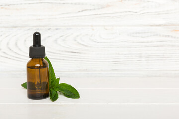 Natural Mint Essential Oil in a Glass Bottle. organic cosmetics with herbal extracts of mint on...
