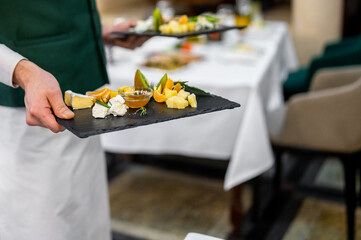hand of a waiter hold plate with cheese food in restaurant