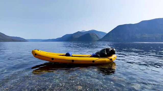 Kayak with backpack on blue lake. Good whether on sunny summer day, Teletskoye lake, Russia. Calm and serenity landscape.