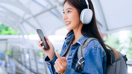 Portrait of happy young asian woman listening music online with wireless headphones from a...