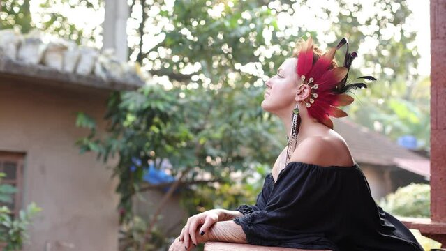Beautiful decoration made of colorful feathers on her head is charming woman in black dress.