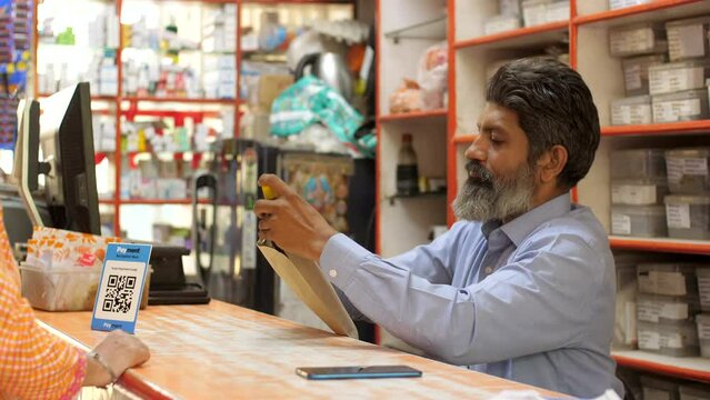 Pharmacists give medicines to the customer after packing them in an envelope at the medical store . Indian chemist giving medicines to the customer - the concept of retail pharmacy store  professio...