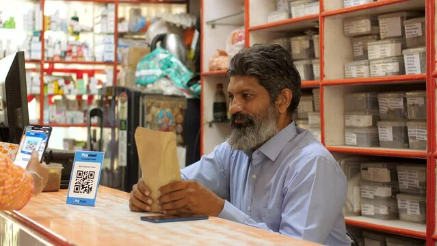 Customer paying money by scanning QR code at the medical shop - cashless payment  contactless transaction  secure payment system. An Indian chemist is receiving digital payments directly into his b...