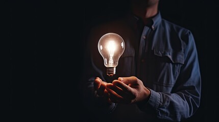 Man hand holding light bulb glowing in the dark. Concept of a person who gets an idea or inspiration.
