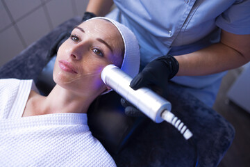 Closeup of face of beautiful relaxing girl undergoing hardware cosmetology procedure in spa