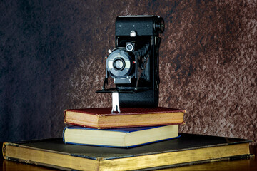 Vintage Folding Film Camera and Old Books on a Wooden Shelf - 705737442