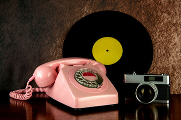 Vintage Telephone with Film Camera and Long Playing Record on a Polished Wooden Table Top - 705737459
