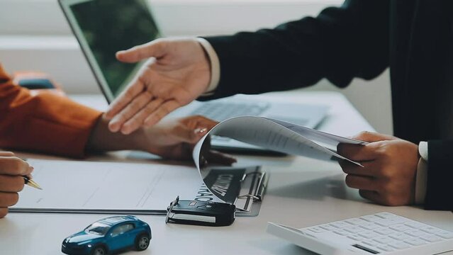 Salesman guiding customer seated at table. Car business. Car sale. Dealership closing. and the new owner has entered into a contract The idea of ​​selling and renting a car with insurance.