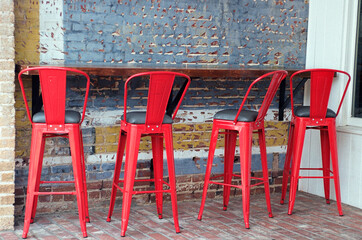 Three red chairs again a brick building.	